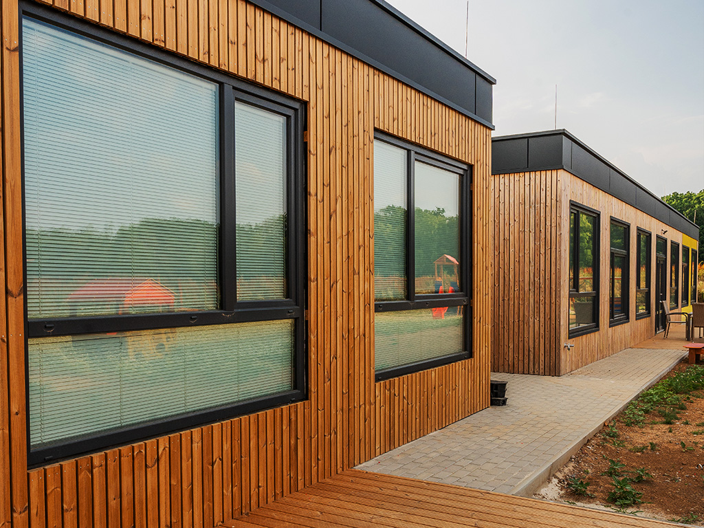 Bürocontainer mit Holzfassade und großen Fenstern