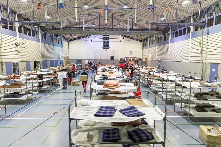 Temporäre Notunterkunft in einer Sporthalle mit Betten und Hilfskräften